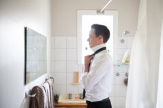 A person stands in front of the mirror in their bathroom, dressing for a job interview.